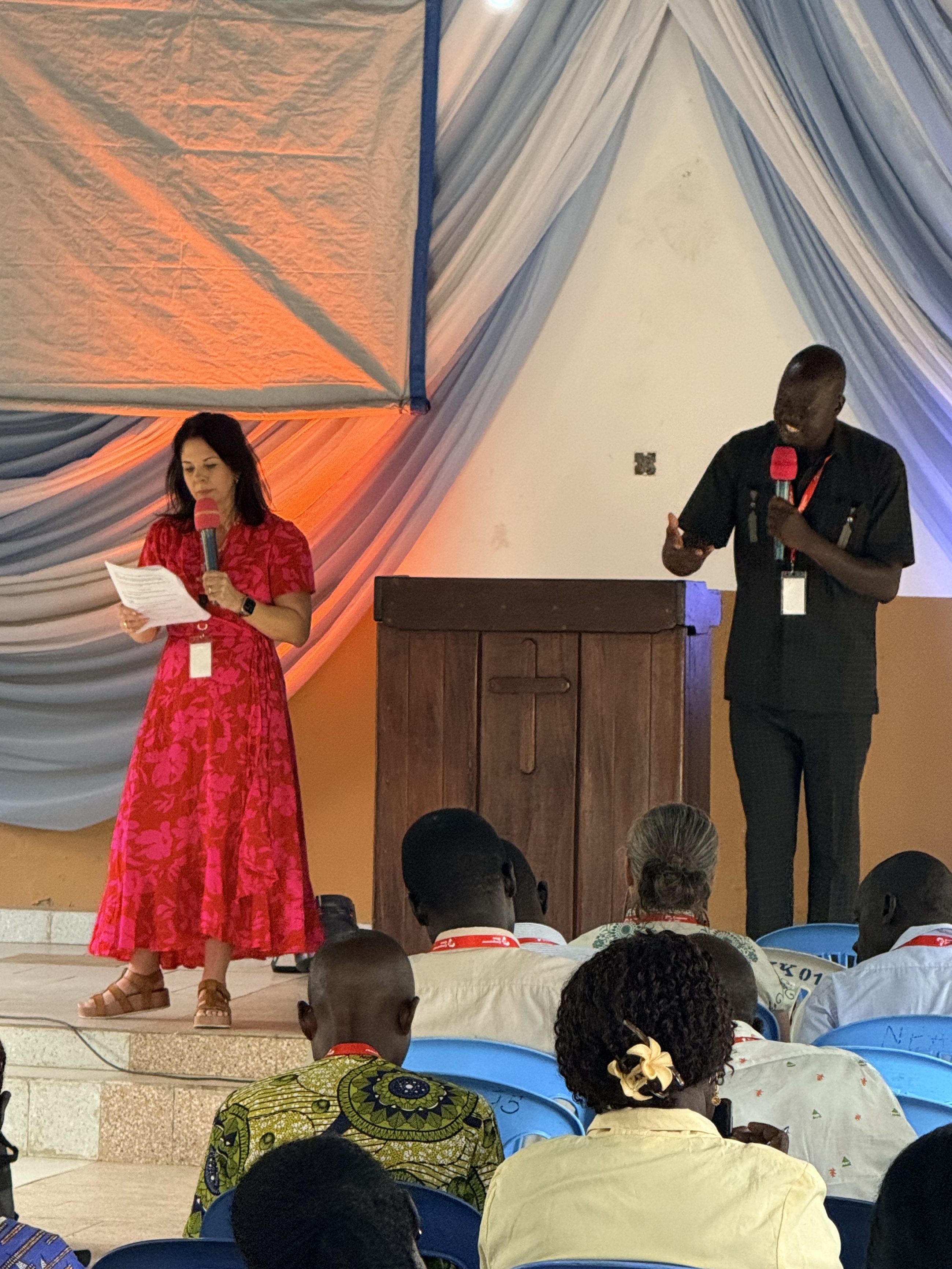 Jodi speaking from a stage beside a translator in Northeast Africa